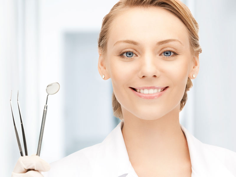 Woman smiling with white teeth holding up dental tools