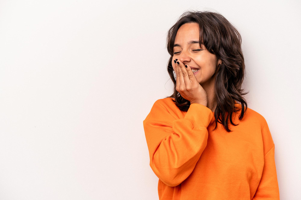 Young Hispanic woman covering her laugh isolated on white background laughing happy carefree natural emotion