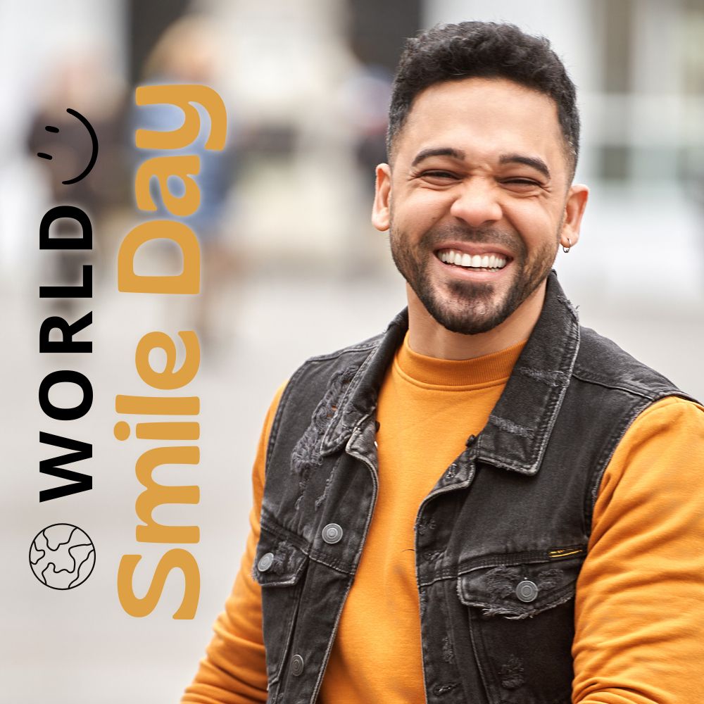 Man in yellow-orange sweatshirt smiling while walking. world smile day graphic.
