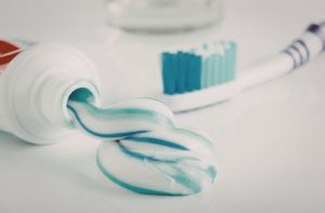 white and blue swirl of fluoride toothpaste next to toothbrush for Pros and Cons of Hydroxyapatite Toothpaste article